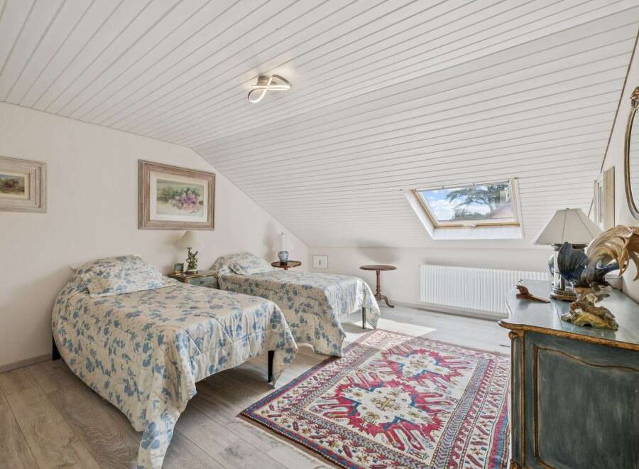 Discover this charming attic bedroom featuring two cozy twin beds adorned with blue floral bedding.