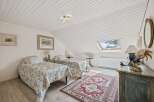 Discover this charming attic bedroom featuring two cozy twin beds adorned with blue floral bedding.