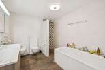 This spacious bathroom features a modern white bathtub, a separate shower area with decorative tile accents, and a sleek vanity with a large sink.