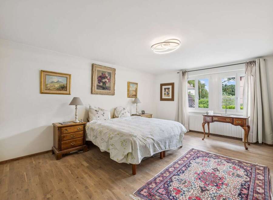 This charming bedroom features a comfortable bed adorned with a floral duvet, complemented by two bedside tables and elegant lamps.