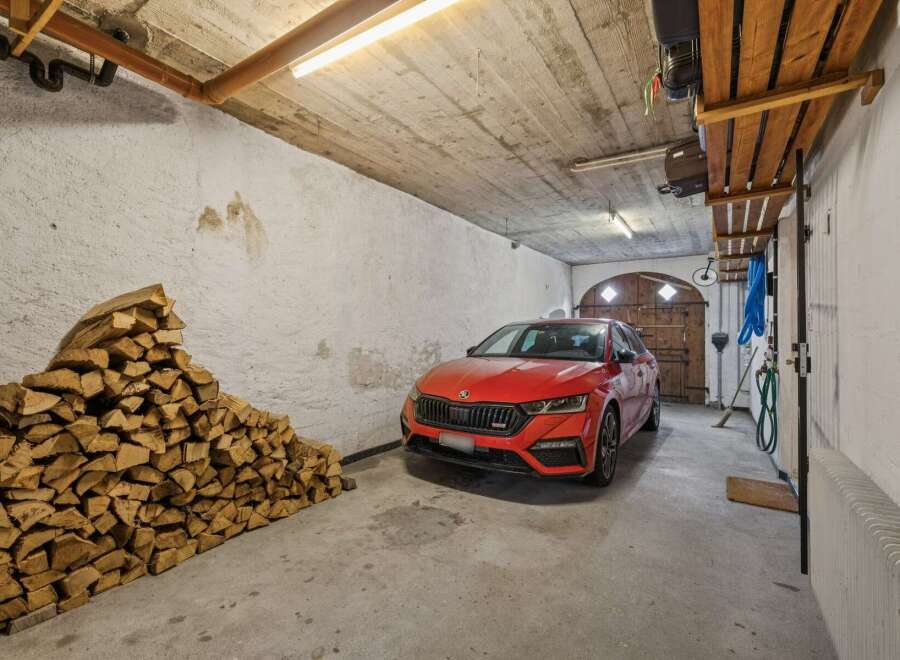 Discover this spacious garage featuring a vibrant red car parked indoors, ready for your next adventure.