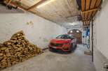 Discover this spacious garage featuring a vibrant red car parked indoors, ready for your next adventure.