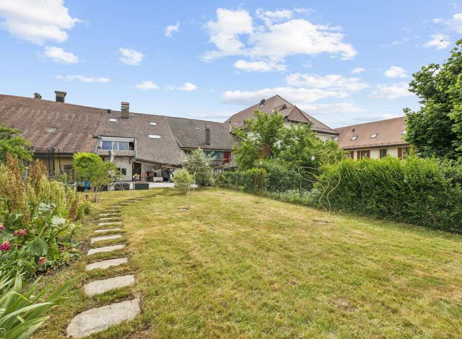 Discover this charming backyard featuring a winding stone pathway leading through a lush green lawn.