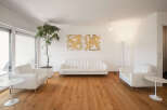 Experience modern living in this bright and airy living room, featuring a sleek white sofa and matching armchairs perfect for relaxation.