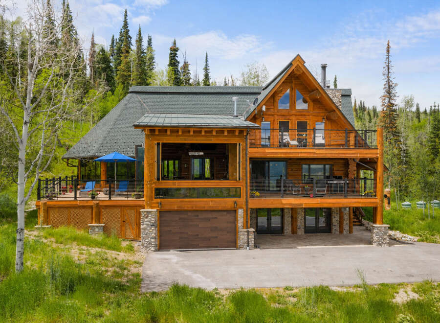 Experience luxury mountain living in this stunning log home, nestled amidst a serene forest landscape.