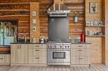 Experience rustic charm in this log cabin kitchen, featuring a professional Wolf range and a sleek stainless steel hood.