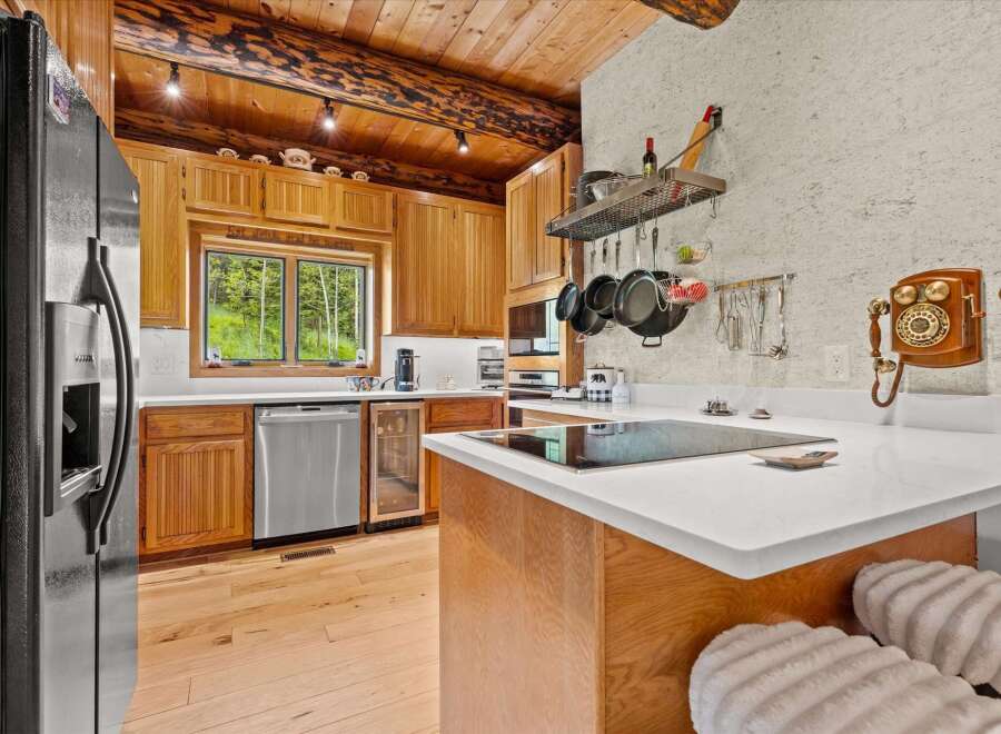 Experience rustic charm in this beautifully appointed kitchen, featuring warm wood cabinetry and exposed log beams.