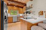 Experience rustic charm in this beautifully appointed kitchen, featuring warm wood cabinetry and exposed log beams.