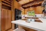 Experience rustic charm in this spacious kitchen featuring warm wood cabinetry and a stunning log beam ceiling.