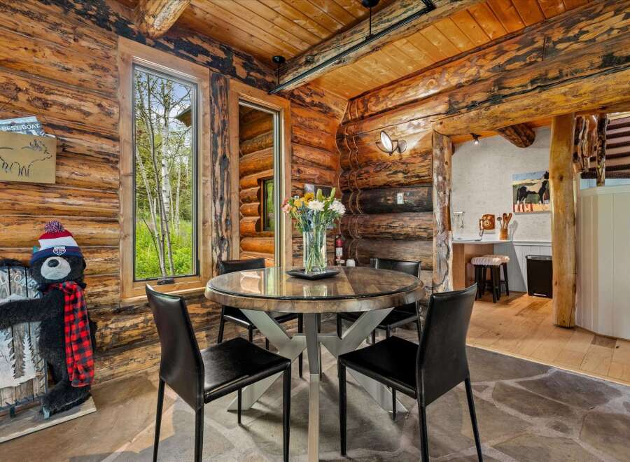 Experience rustic charm in this cozy dining area, featuring a round wooden table with a glass top, perfect for intimate meals.