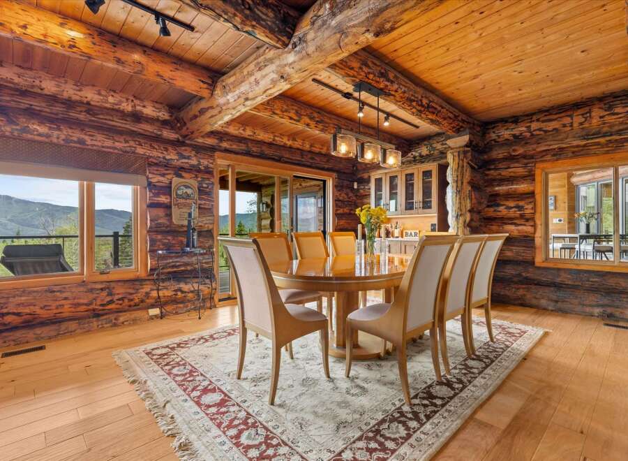 Experience rustic luxury in this stunning log home dining room, featuring a grand wooden table perfect for gatherings and surrounded by plush seating.