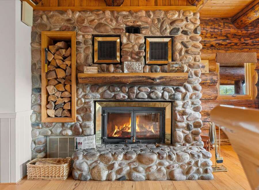 Cozy up by the stunning stone fireplace, complete with a rustic log mantel and a glass-enclosed firebox, perfect for chilly evenings.