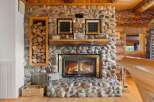 Cozy up by the stunning stone fireplace, complete with a rustic log mantel and a glass-enclosed firebox, perfect for chilly evenings.