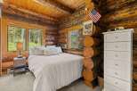 Experience rustic charm in this cozy log cabin bedroom, featuring a comfortable bed adorned with plush pillows and a textured duvet.