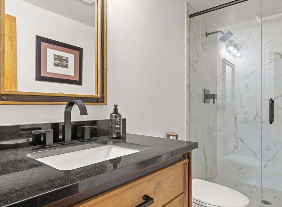 Experience modern luxury in this stunning bathroom featuring a sleek vanity with a granite countertop and a contemporary black faucet.