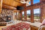Experience rustic luxury in this stunning log cabin living room, featuring a grand stone fireplace and exposed wooden beams.