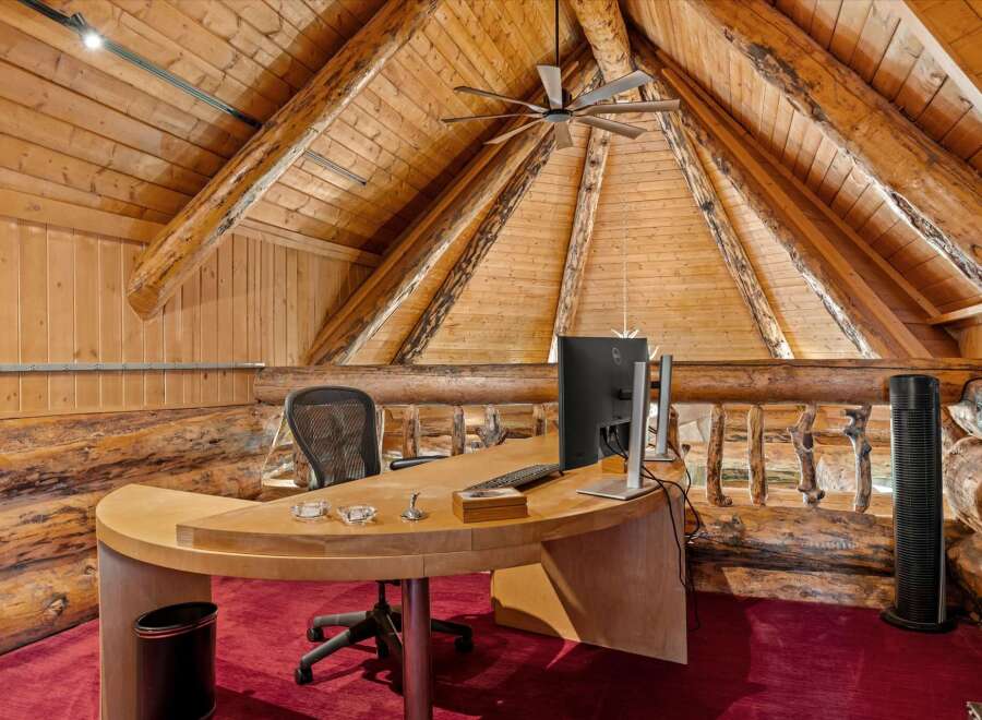 Experience rustic luxury in this unique office space, featuring a stunning log cabin aesthetic with exposed wooden beams and a vaulted ceiling.