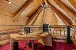 Experience rustic luxury in this unique office space, featuring a stunning log cabin aesthetic with exposed wooden beams and a vaulted ceiling.