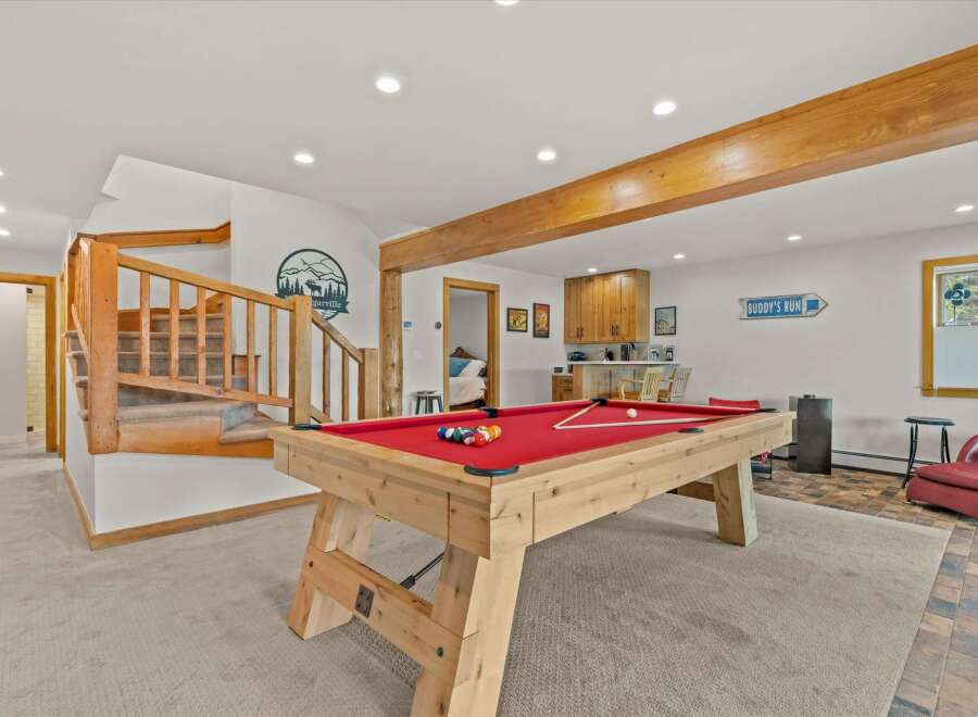 Enjoy endless entertainment in this basement game room, featuring a classic billiard table perfect for friendly competitions.
