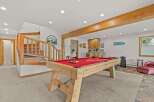 Enjoy endless entertainment in this basement game room, featuring a classic billiard table perfect for friendly competitions.