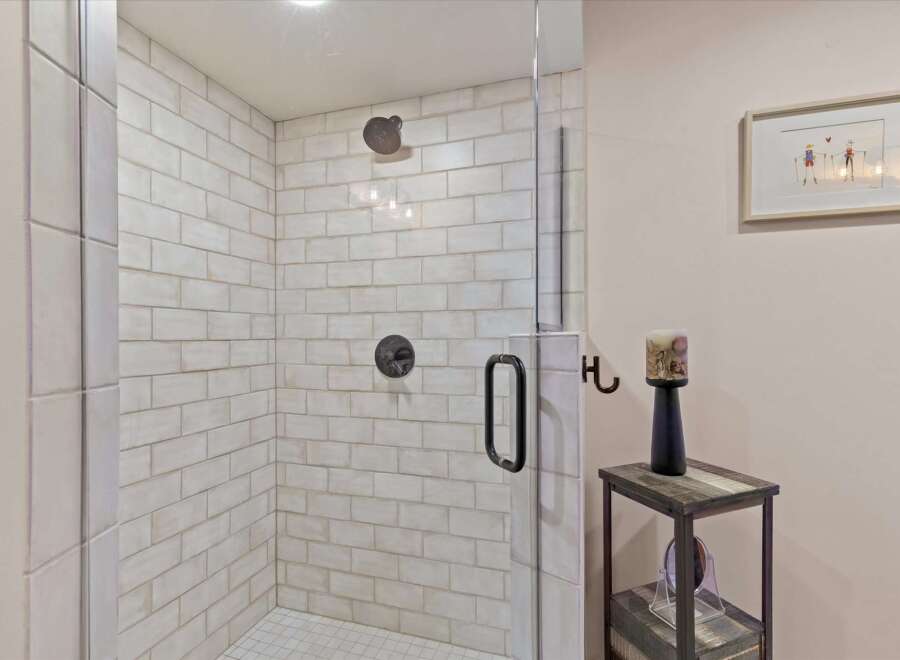 Step into this beautifully appointed bathroom featuring a spacious walk-in shower with classic subway tile and modern black fixtures.