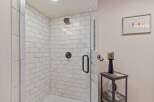Step into this beautifully appointed bathroom featuring a spacious walk-in shower with classic subway tile and modern black fixtures.