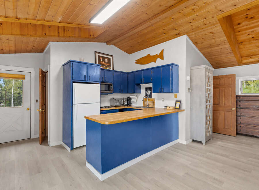 Discover this charming kitchen featuring vibrant blue cabinetry and a butcher block countertop, perfect for meal preparation.