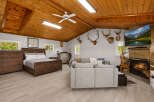 Experience rustic charm in this unique bedroom and living space, featuring a cozy wooden ceiling, a comfortable bed, and a fireplace with a mounted TV.