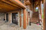 Experience rustic charm with this stunning log home featuring a stone foundation and a grand wooden staircase leading to the upper level.