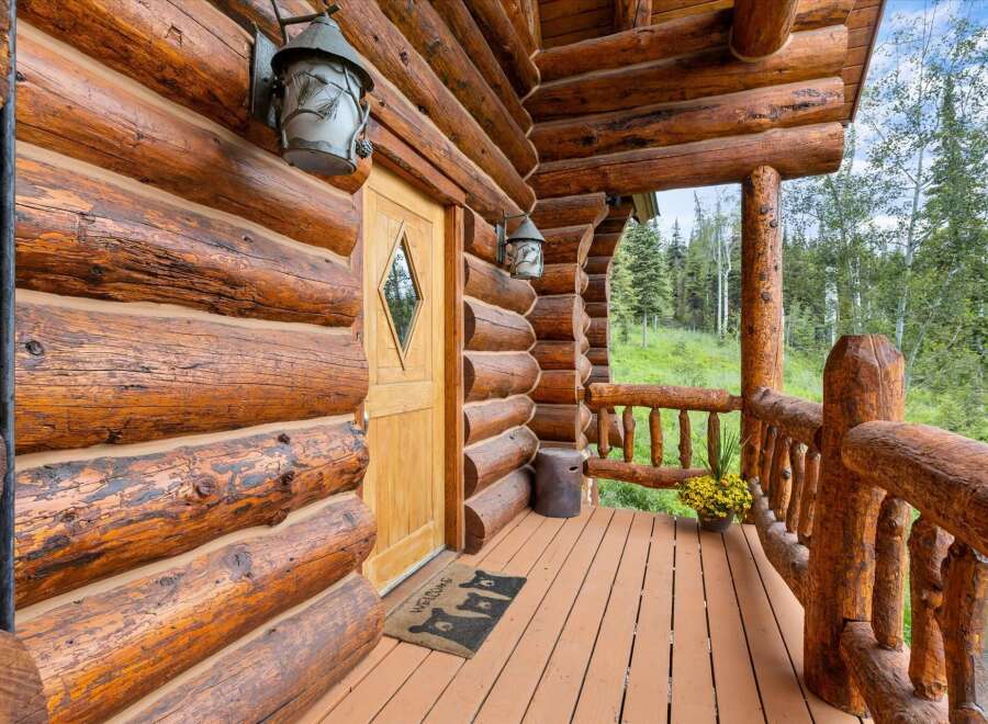 Experience rustic charm with this inviting log cabin entrance, featuring a warm wooden door and a welcoming porch.
