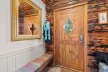 Step into a charming log cabin entryway featuring a rustic wooden door with a diamond-shaped window, perfect for letting in natural light.