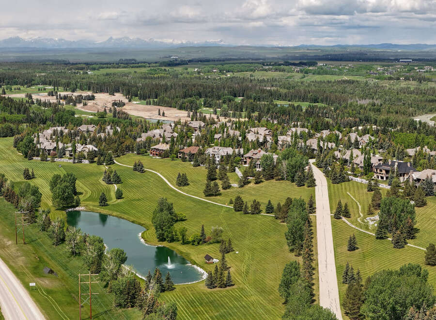 Discover luxury living in this stunning aerial view of a sprawling estate, featuring meticulously manicured lawns and a serene pond with a fountain.