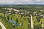 Discover luxury living in this stunning aerial view of a sprawling estate, featuring meticulously manicured lawns and a serene pond with a fountain.