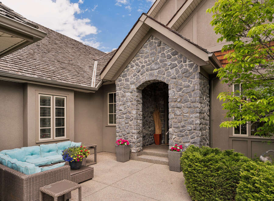 Experience elegant outdoor living with this charming patio featuring a comfortable wicker sectional sofa adorned with vibrant blue cushions.