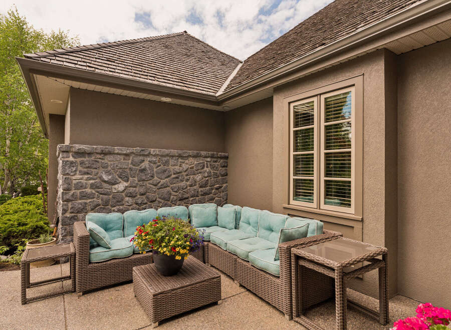Enjoy outdoor living with this spacious patio featuring a comfortable sectional sofa and a charming coffee table adorned with a vibrant floral arrangement.
