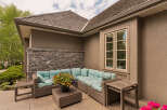 Enjoy outdoor living with this spacious patio featuring a comfortable sectional sofa and a charming coffee table adorned with a vibrant floral arrangement.