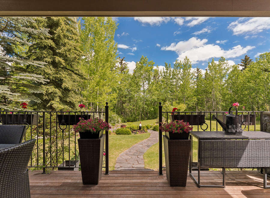 Enjoy your morning coffee on this charming covered deck, overlooking a beautifully landscaped backyard with a winding stone pathway.