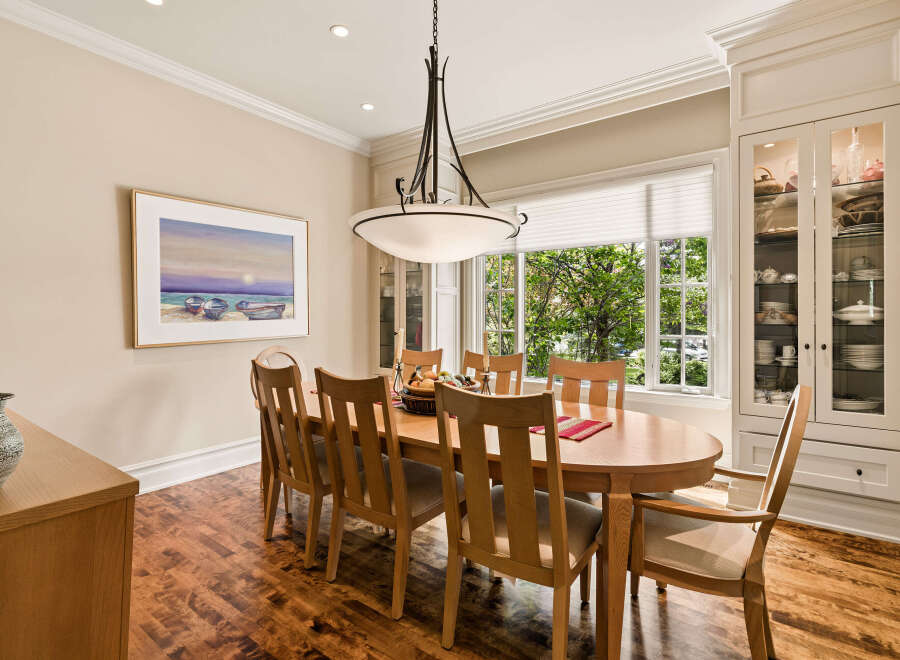 This elegant dining room features a large oval wooden table with eight chairs, perfect for hosting family gatherings.