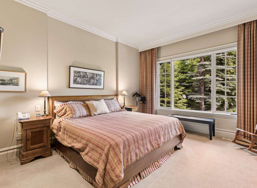 Experience serene mountain living in this charming bedroom, featuring a comfortable king-size bed adorned with a striped comforter and plush pillows.