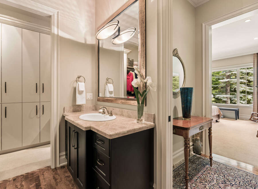 This luxurious bathroom features a spacious vanity with a marble countertop and a modern dark wood cabinet.