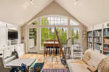 Discover an artist's dream studio bathed in natural light, featuring a large arched window with stunning forest views.