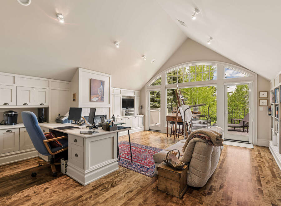 This spacious home office features a large desk with dual monitors, ample cabinetry, and a comfortable seating area.
