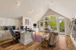 This spacious home office features a large desk with dual monitors, ample cabinetry, and a comfortable seating area.