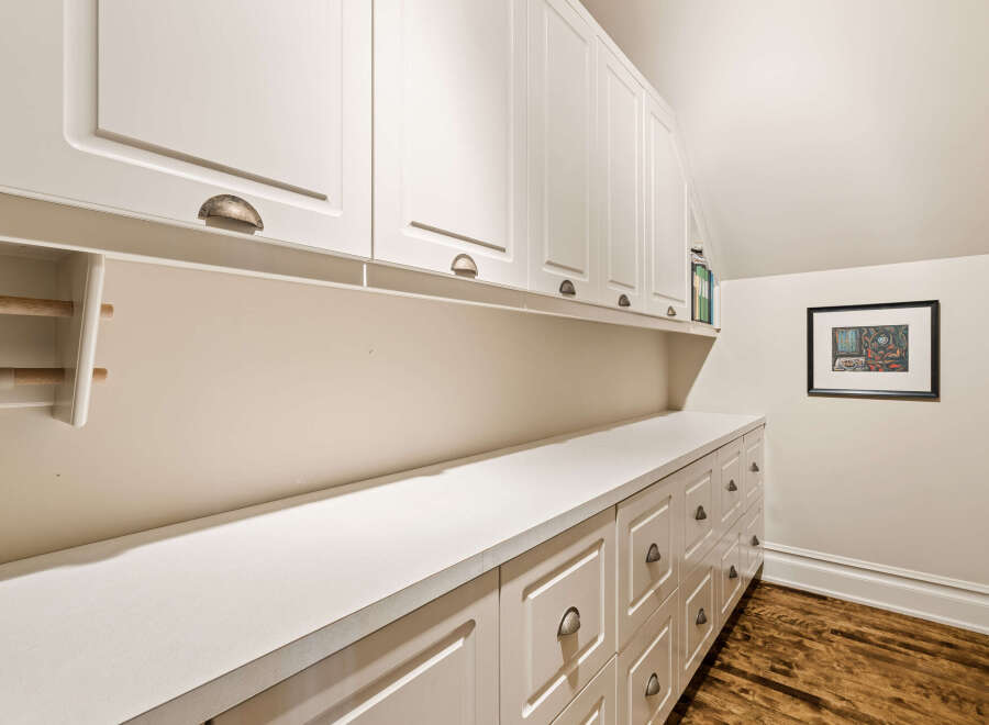 Discover ample storage solutions in this home, featuring a long stretch of white cabinetry with both upper cabinets and lower drawers.