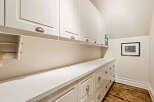 Discover ample storage solutions in this home, featuring a long stretch of white cabinetry with both upper cabinets and lower drawers.