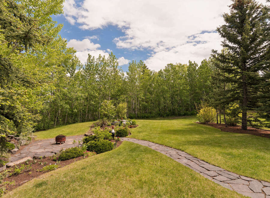 Discover this stunning property featuring a beautifully landscaped backyard with a winding stone pathway leading to a serene garden area.