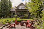 Enjoy the outdoors with this charming backyard featuring a stone patio, a fire pit, and comfortable Adirondack chairs perfect for gathering.