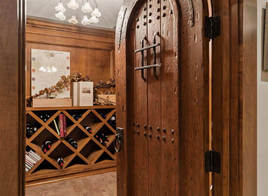 Step into this exquisite wine cellar, featuring a rustic, arched wooden door with decorative metal accents.