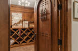 Step into this exquisite wine cellar, featuring a rustic, arched wooden door with decorative metal accents.