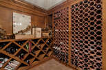 Discover this exquisite wine cellar, featuring a custom-built wooden wine rack system with diamond-shaped compartments perfect for storing your collection.
